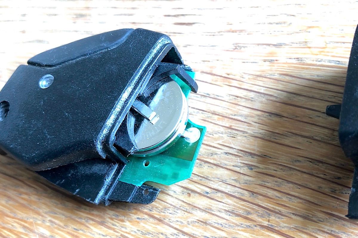 リモコン・ロックの動きが怪しいのでキー・ケース内部を分解すると、本来ボタン電池（CR2025）が2つ入っているべきところに、別の規格の電池が混入していた。