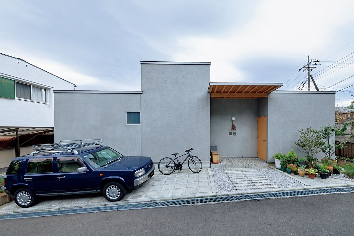 クリーンな造形の玄関側の眺め。平屋だが、部屋によって天井高が異なるのが分かる。壁の色とクルマの色が上手くマッチ。