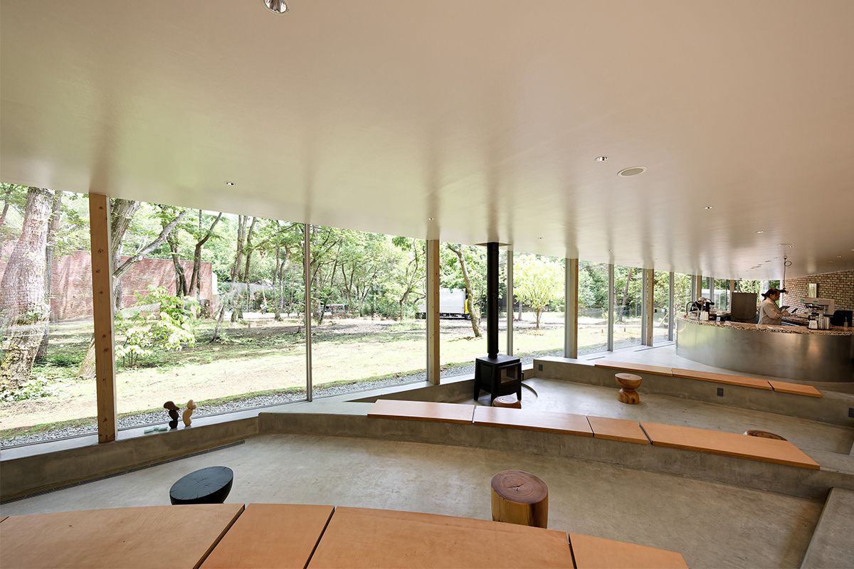 斜面の傾斜を利用したカフェの店内に柱がなく、ガラスの全面開口部のおかげで自然とシームレス感覚。冬は暖炉が活躍しそう。