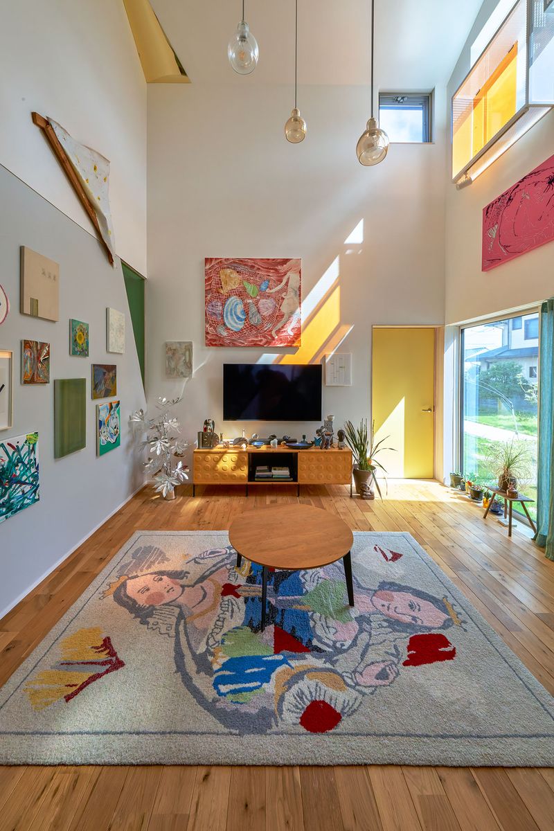 吹き抜けのリビングルーム。ラグに加えテレビ右手の作品が竹村さんの手によるもの。あとの作品は友人の美術家のものが多い。