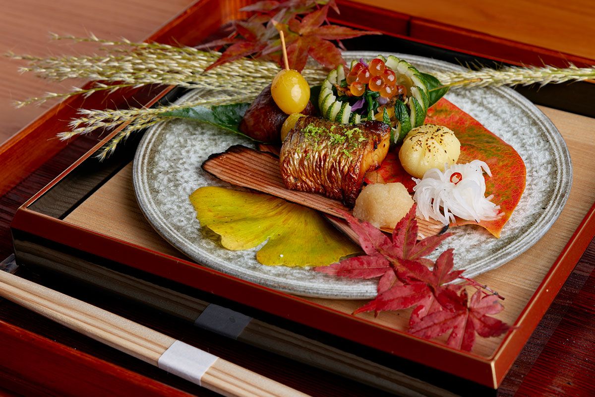 料理は3万6300円~のディナーコースより。写真は山里の澄んだ空気を思わせる清雅な焼八寸。左上から時計回りに揚げ銀杏、栗の渋皮煮、かぼす釜、丸十の茶巾、菊花蕪、染めおろしとカマス柚香焼き。かぼす釜の中は薪で焼いたきのこと菊菜のお浸しと菊花、イクラ。